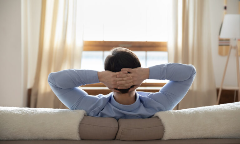 Pessoa relaxando em um sofá com as mãos atrás da cabeça, de frente para uma janela iluminada. Homem relaxando porque tem Flexibilidade no Trabalho para um Equilíbrio Ideal, entre o laser e o trabalho 1. Homem relaxando no sofá, com as mãos atrás da cabeça, simbolizando a flexibilidade no trabalho e o equilíbrio ideal. 2. Homem sentado no sofá, mãos atrás da cabeça, representando a flexibilidade no trabalho e um equilíbrio entre lazer e trabalho. 3. Homem em um sofá, com as mãos atrás da cabeça, ilustrando a flexibilidade no trabalho e a busca por um equilíbrio ideal. 12 Profissões com Flexibilidade no Trabalho para um Equilíbrio Ideal